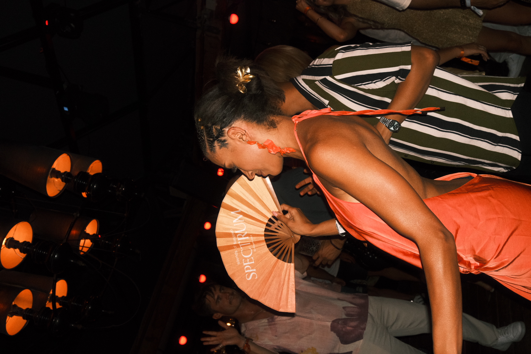 A guest with a Spectrum-branded fan on a warm-lit dance floor