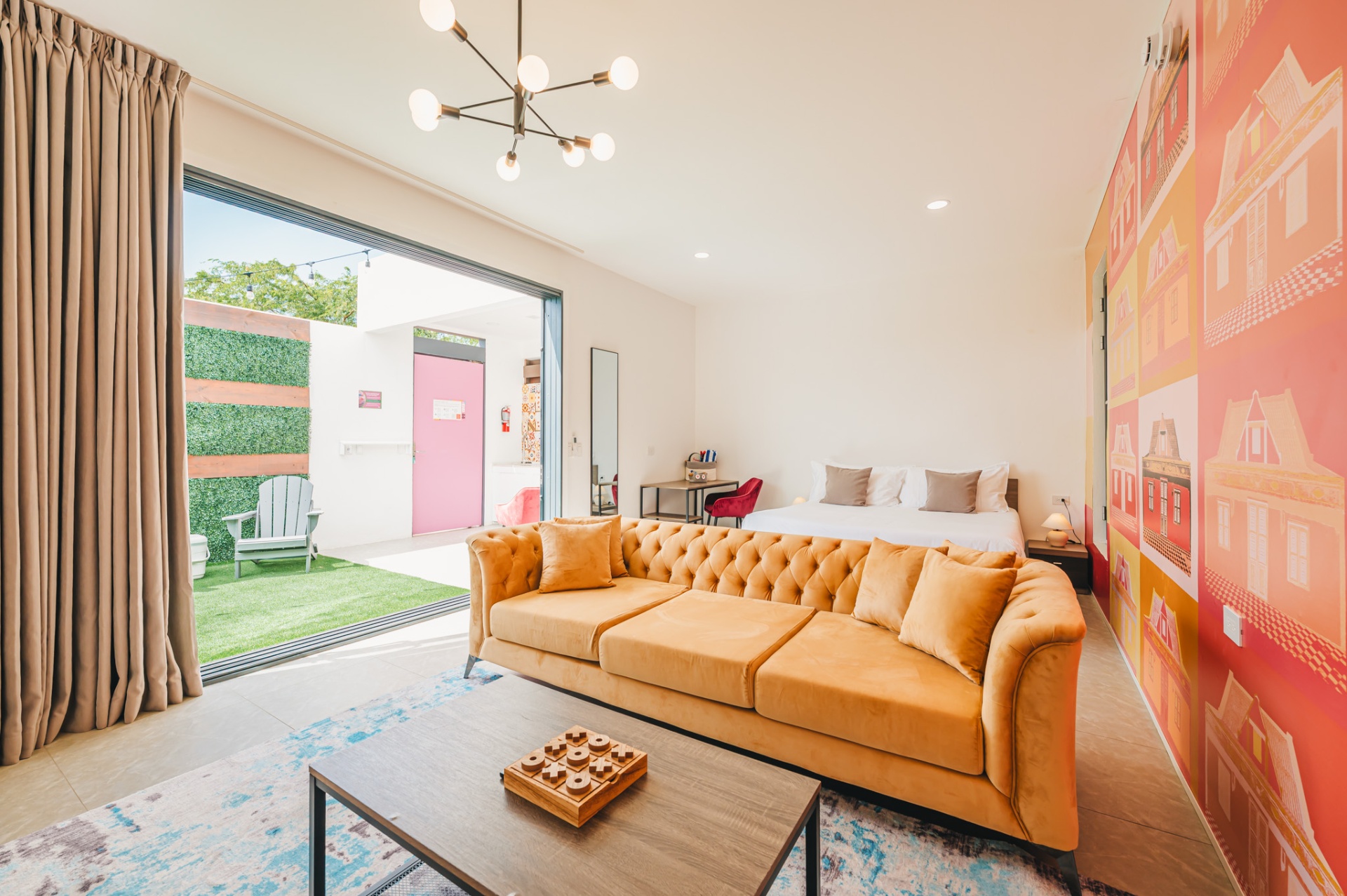 Pop-art Privada suite with orange velvet sofa and mural of Aruban houses