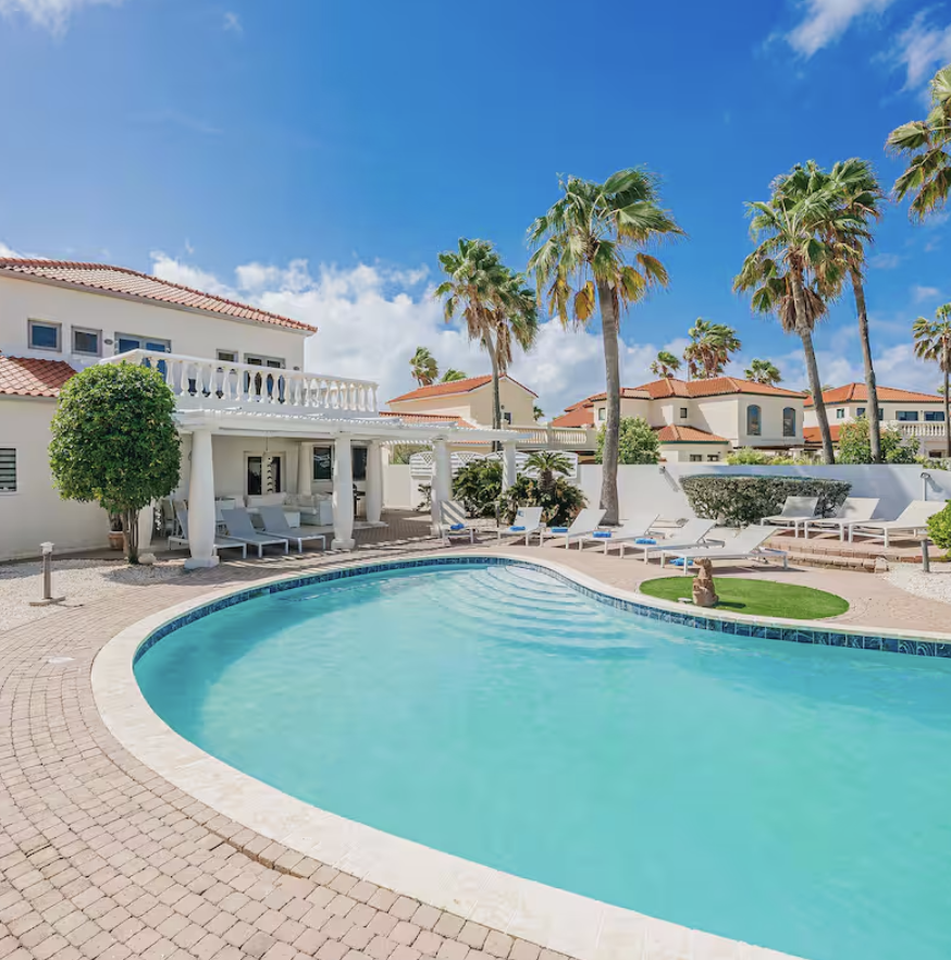 Private villa exterior with palm trees and a curved pool