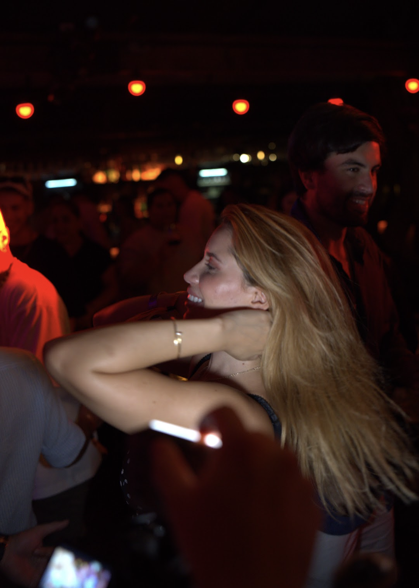 A guest laughs mid-spin on a red-lit dance floor