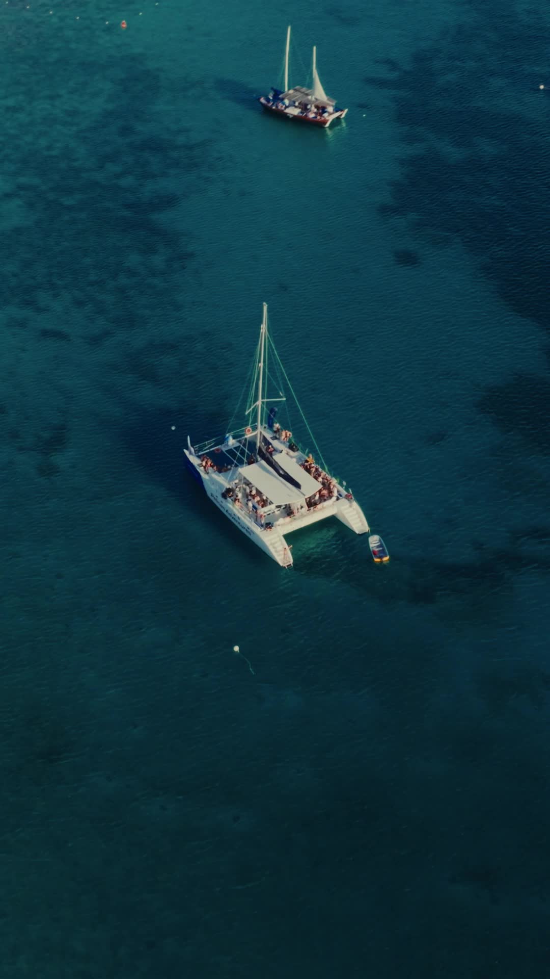 Aerial of catamarans anchored on deep teal Caribbean water — Flow, Sunday
