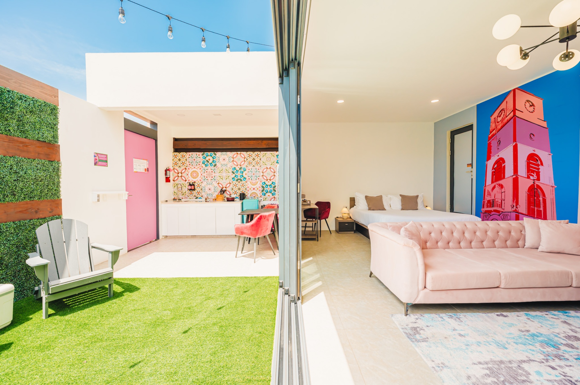 Open suite with pink clocktower mural and adjacent garden patio with kitchenette
