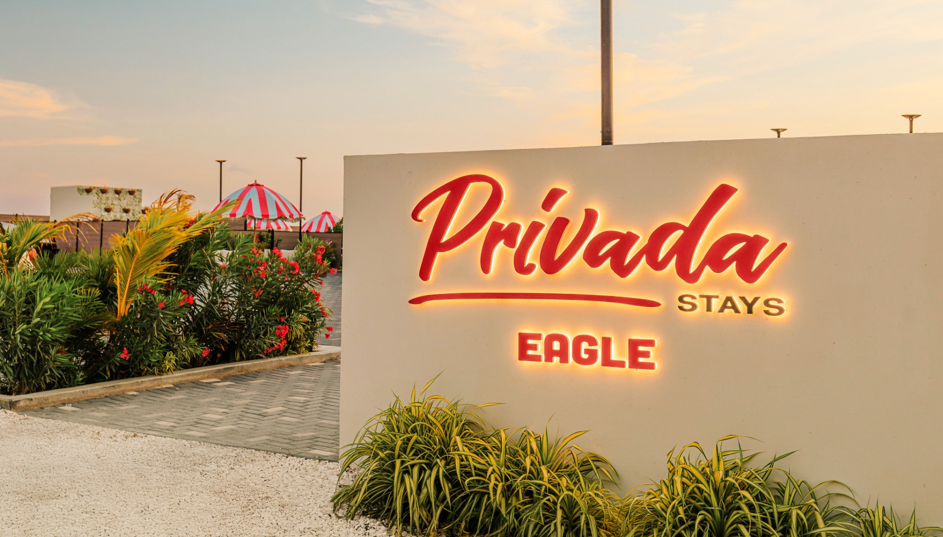 Backlit Privada Stays Eagle sign with cabana umbrellas behind