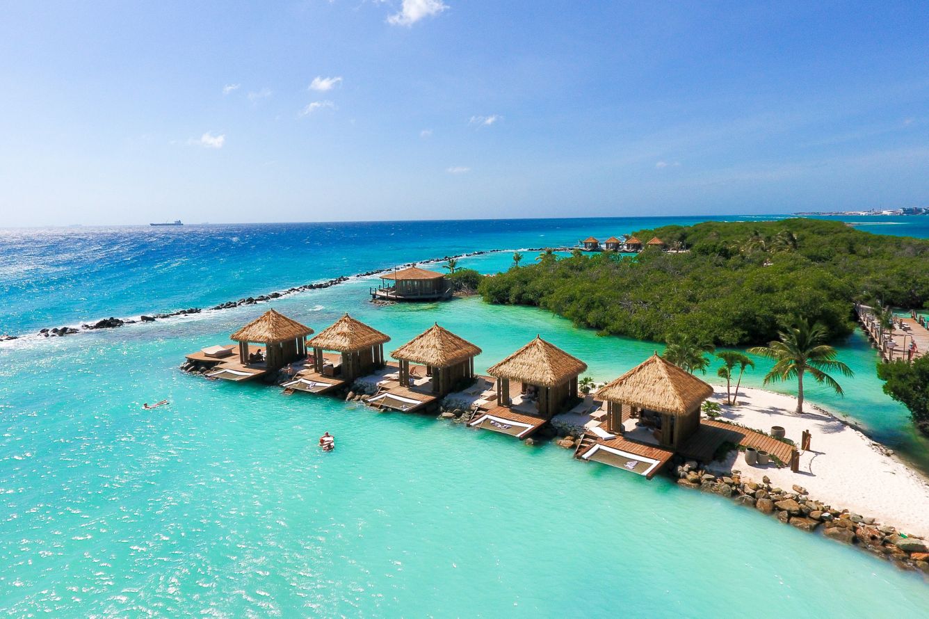 Aerial of overwater thatched cabanas at the resort's private island