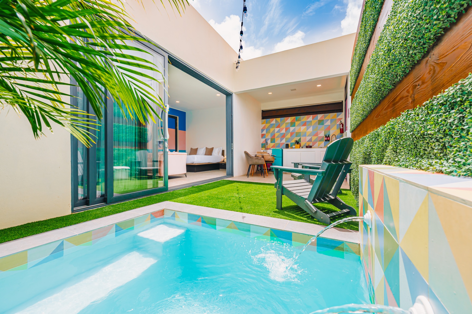 Private suite courtyard with plunge pool, green lawn, outdoor kitchenette, and lounge chair