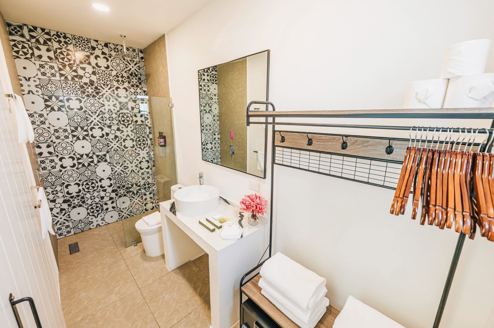 Bathroom with black-and-white patterned tile wall, rain shower, and vessel sink