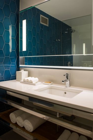 Bathroom with cobalt hexagonal tile, vanity and rolled towels