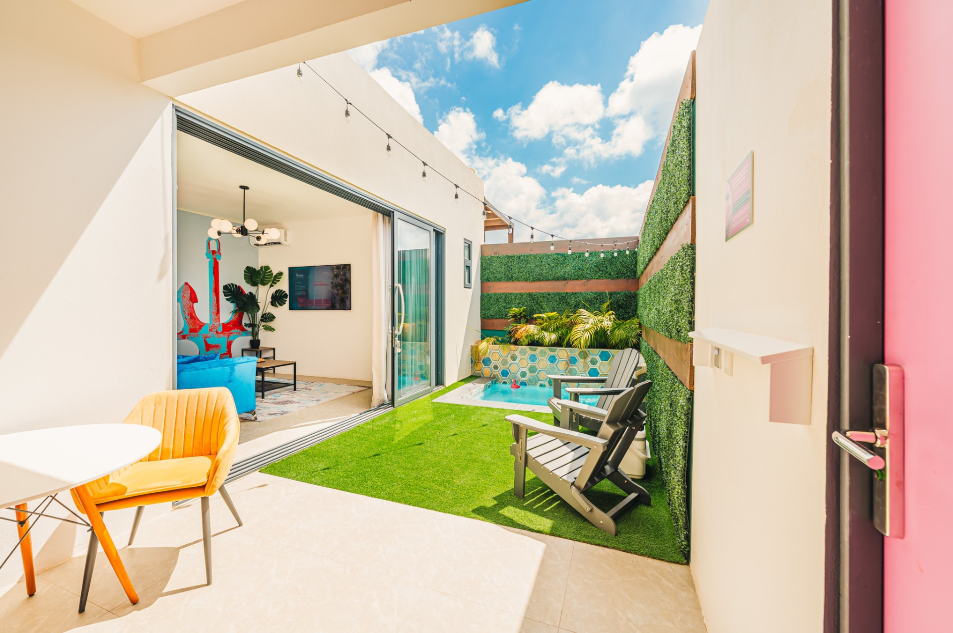 Private patio with plunge pool, lawn, and an anchor mural visible inside the suite